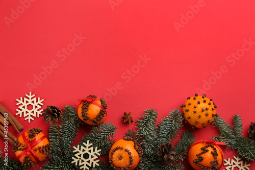 Flat lay composition with pomander balls made of fresh tangerines on red background. Space for text
