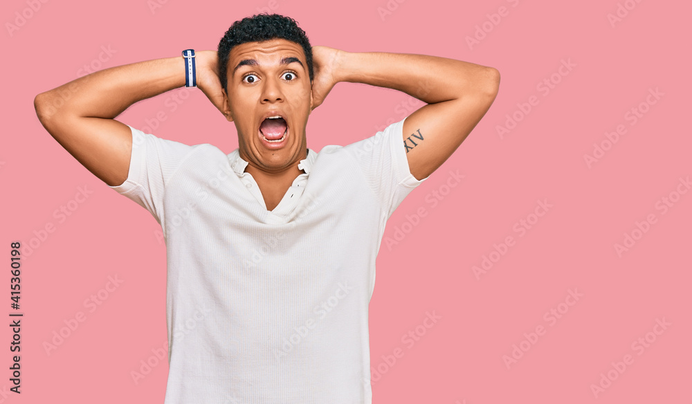 Young arab man wearing casual clothes crazy and scared with hands on head, afraid and surprised of shock with open mouth Young arab man wearing casual clothes crazy and scared with hands on head, afraid and surprised of shock with open mouth