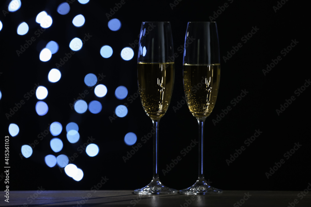 Glasses of champagne on grey table against blurred lights. Space for text Glasses of champagne on grey table against blurred lights. Space for text