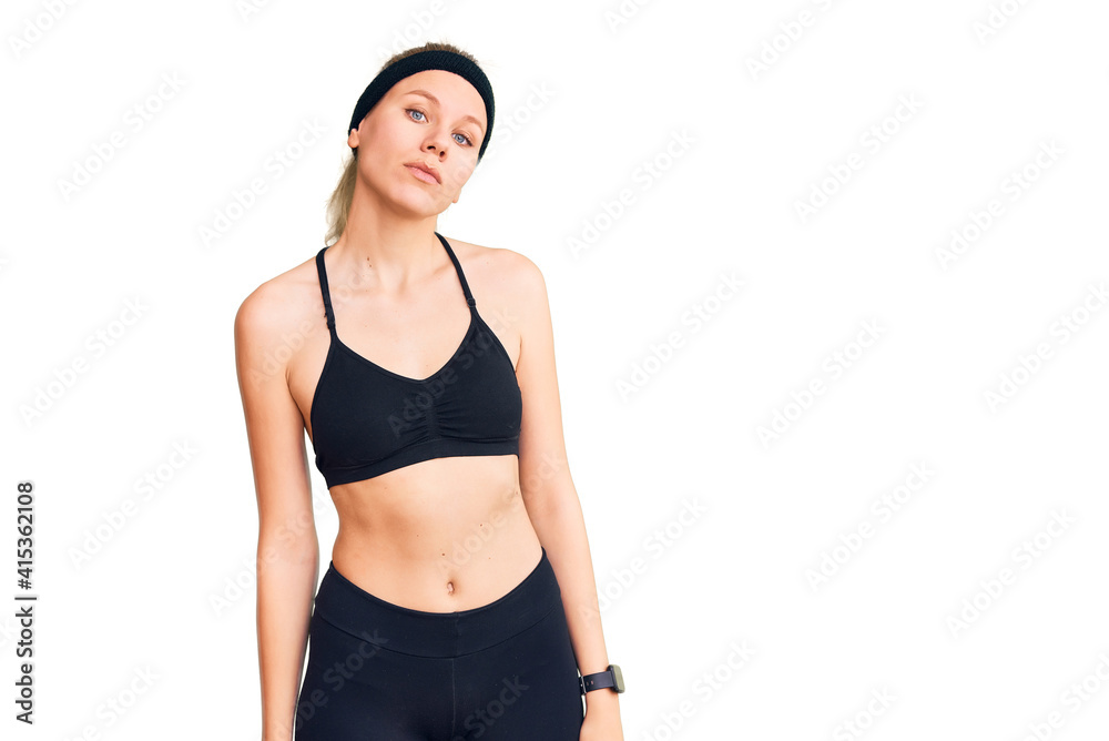 Young beautiful blonde woman wearing sportswear relaxed with serious expression on face. simple and natural looking at the camera. Young beautiful blonde woman wearing sportswear relaxed with serious expression on face. simple and natural looking at the camera.