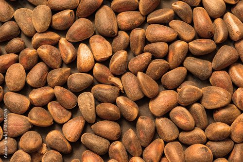 Background unpeeled Siberian pine nuts in a shell close-up. 