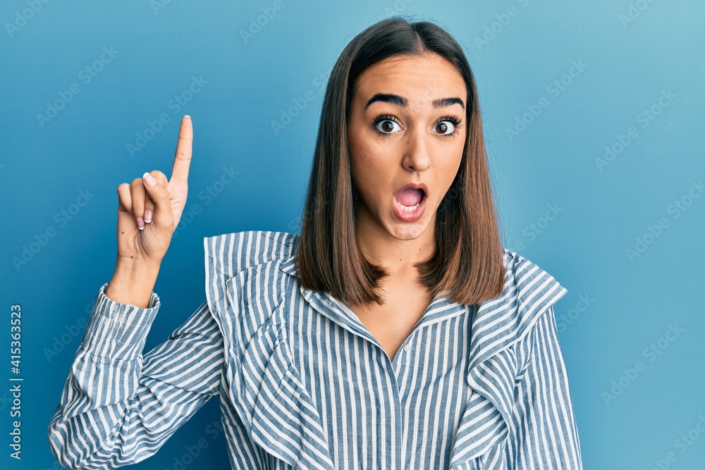 Young brunette student girl pointing up with finger afraid and shocked with surprise and amazed expression, fear and excited face. Young brunette student girl pointing up with finger afraid and shocked with surprise and amazed expression, fear and excited face.