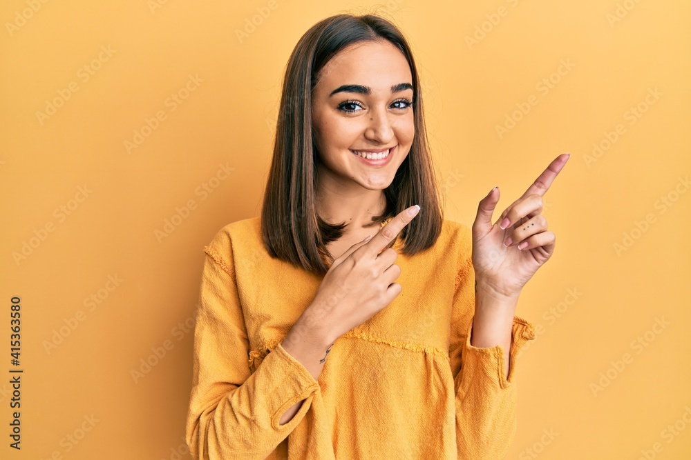 Young brunette girl wearing casual clothes smiling and looking at the camera pointing with two hands and fingers to the side. Young brunette girl wearing casual clothes smiling and looking at the camera pointing with two hands and fingers to the side.