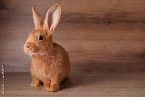 Cute bunny on table against wooden background, space for text. Easter symbol