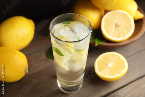 Cool freshly made lemonade and fruits on wooden table, closeup