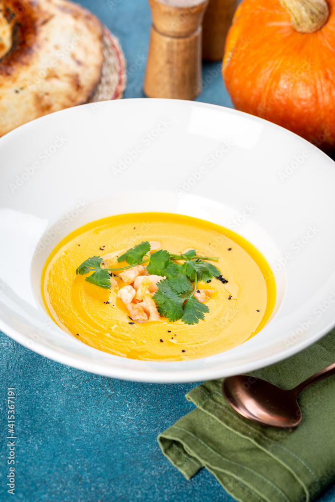 Pumpkin soup in a white plate filmed in decor Pumpkin soup in a white plate filmed in decor
