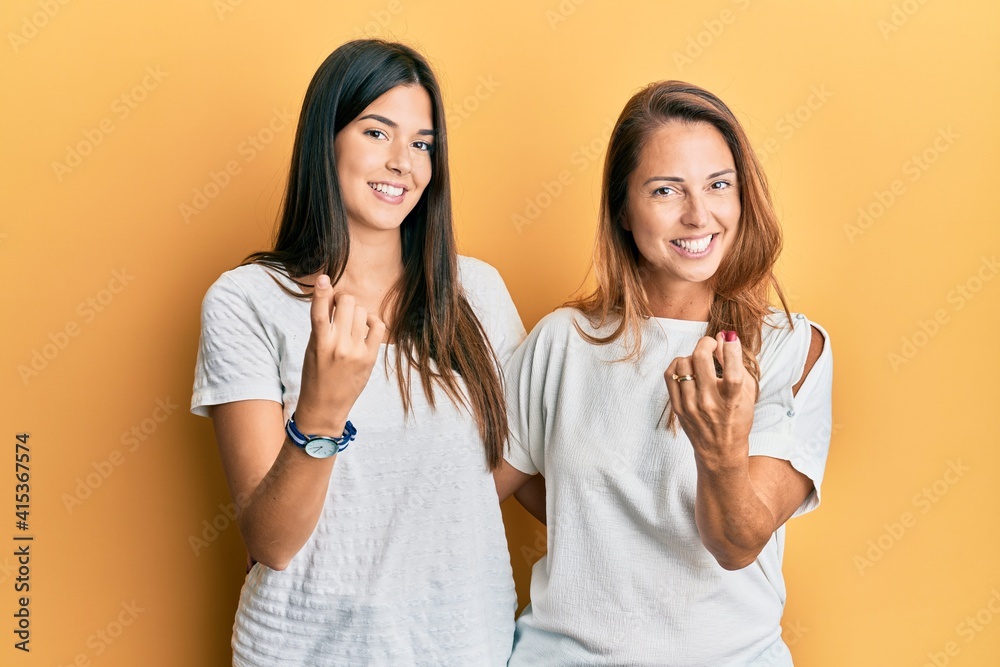 Hispanic family of mother and daughter wearing casual white tshirt beckoning come here gesture with hand inviting welcoming happy and smiling Hispanic family of mother and daughter wearing casual white tshirt beckoning come here gesture with hand inviting welcoming happy and smiling