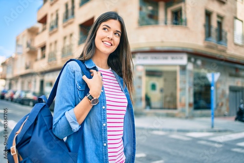 Young hispanic student girl smiling happy walking at the city.