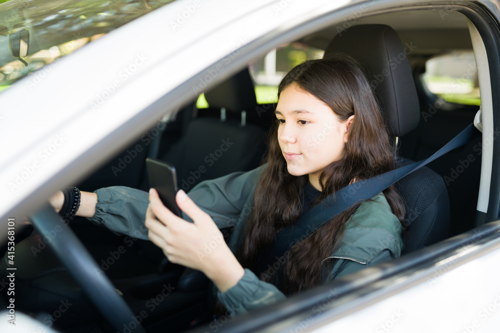 Cute teenage girl using her phone while driving Cute teenage girl using her phone while driving