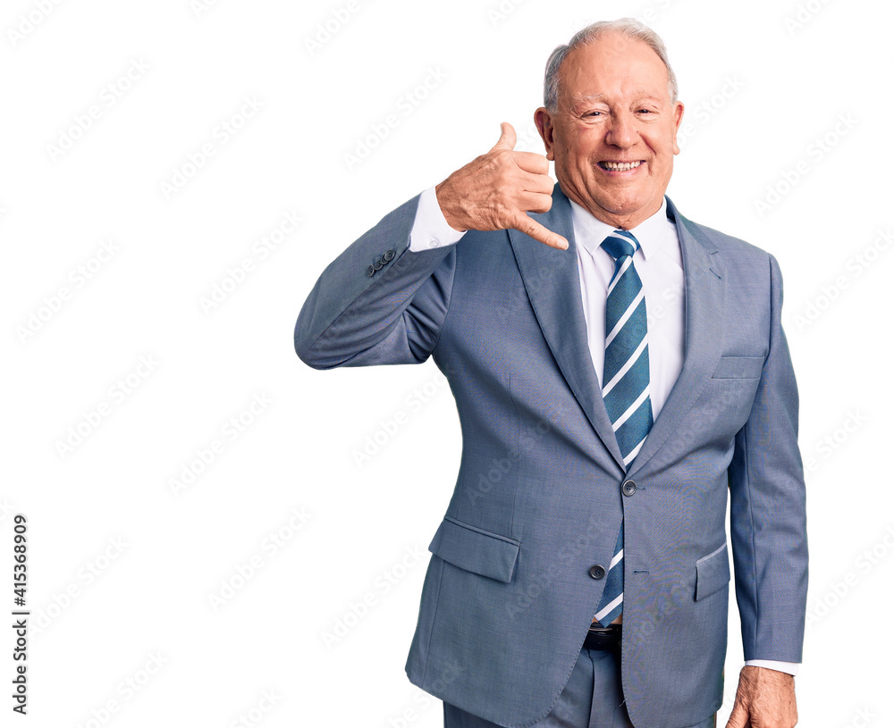 Senior handsome grey-haired man wearing elegant suit smiling doing phone gesture with hand and fingers like talking on the telephone. communicating concepts. Senior handsome grey-haired man wearing elegant suit smiling doing phone gesture with hand and fingers like talking on the telephone. communicating concepts.