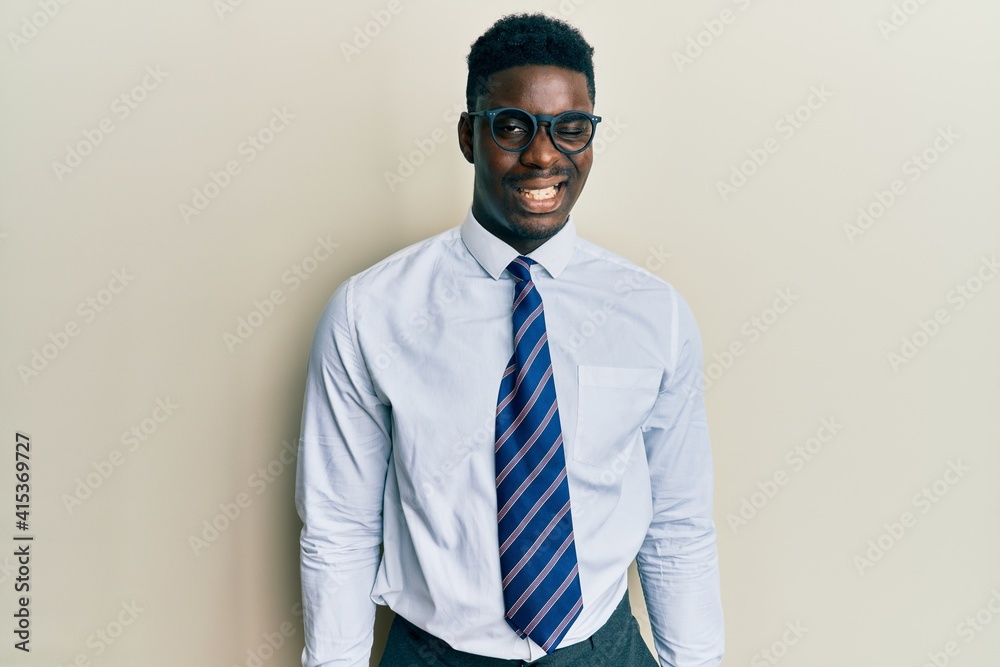Handsome black man wearing glasses business shirt and tie winking looking at the camera with sexy expression, cheerful and happy face. Handsome black man wearing glasses business shirt and tie winking looking at the camera with sexy expression, cheerful and happy face.