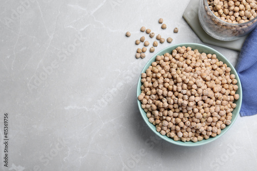 Chickpeas in bowl on light grey table, flat lay. Space for text