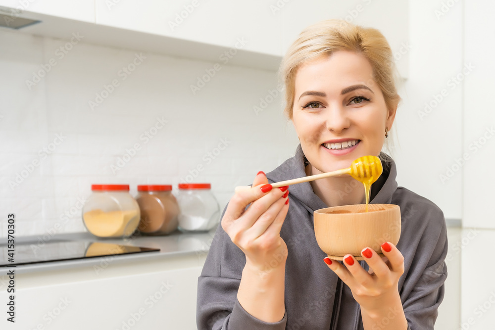 Young Happy Woman holding honey Enjoying While cooking healthy food In Kitchen. Detox Diet, Weight Loss Nutrition Concept Young Happy Woman holding honey Enjoying While cooking healthy food In Kitchen. Detox Diet, Weight Loss Nutrition Concept