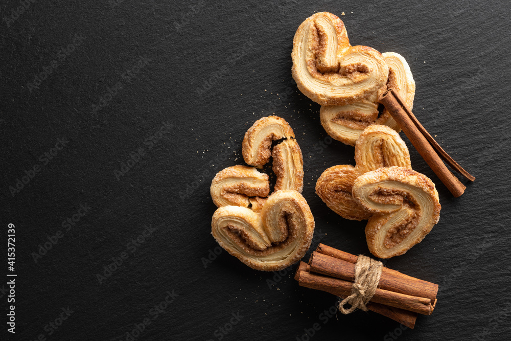 crispy puff pastry with sugar and cinnamon on a black stone background, top view, place for text crispy puff pastry with sugar and cinnamon on a black stone background, top view, place for text