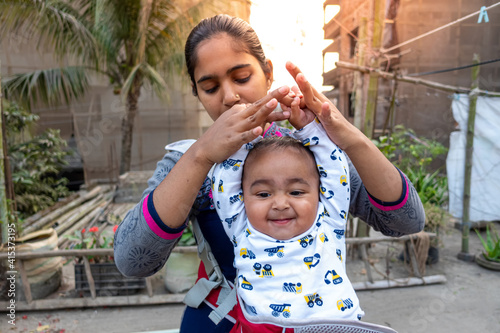 Mom is playing with his cute chubby baby boy in the afternoon time at the rooftop. Mother-baby care and motor development concept. photo