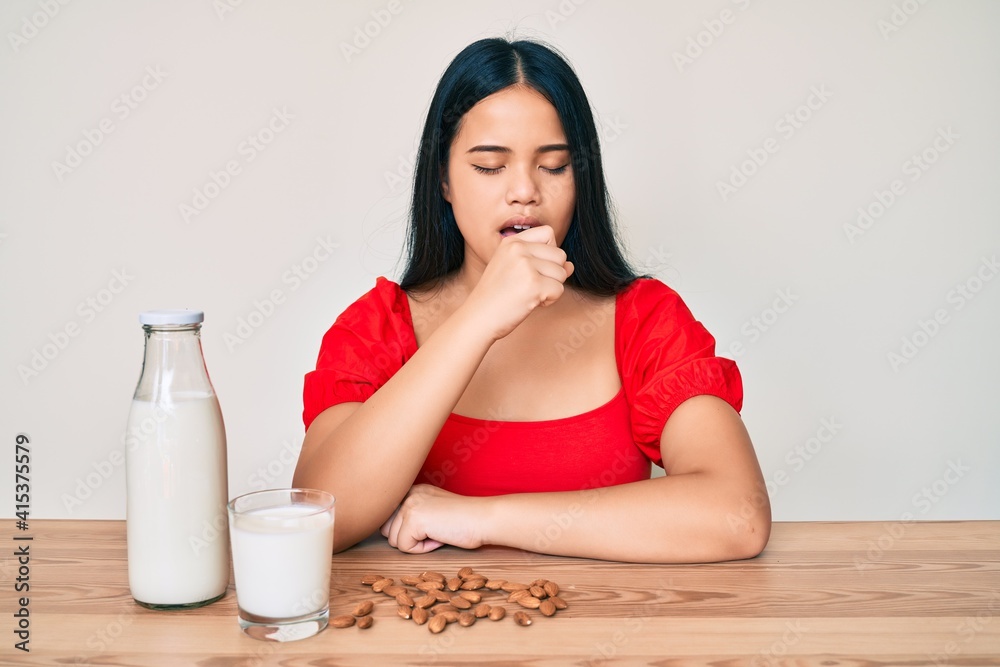 Young asian girl drinking healthy almond milk feeling unwell and coughing as symptom for cold or bronchitis. health care concept. Young asian girl drinking healthy almond milk feeling unwell and coughing as symptom for cold or bronchitis. health care concept.