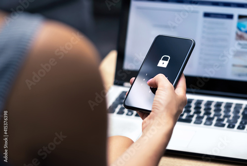 Phishing, mobile phone hacker or cyber scam concept. Password and login pass code in smartphone. Online security threat and fraud. Female scammer with cellphone and laptop. Bank account security. photo