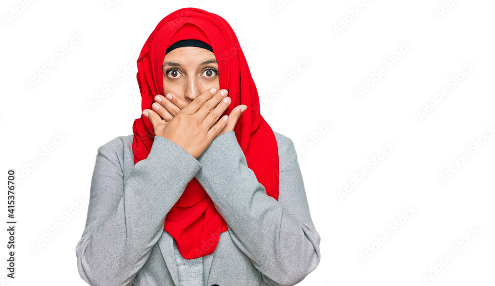 Beautiful hispanic woman wearing traditional islamic hijab scarf shocked covering mouth with hands for mistake. secret concept.