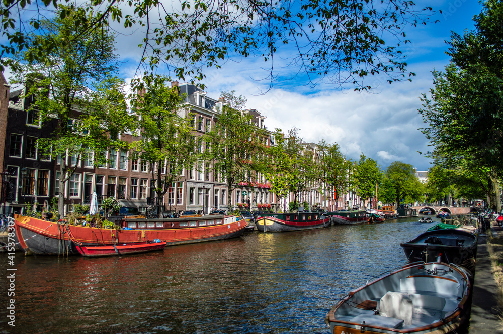 Fototapeta premium Amsterdam, Netherlands - July 7, 2019: Houseboats docked in the canals of Amsterdam in the Netherlands