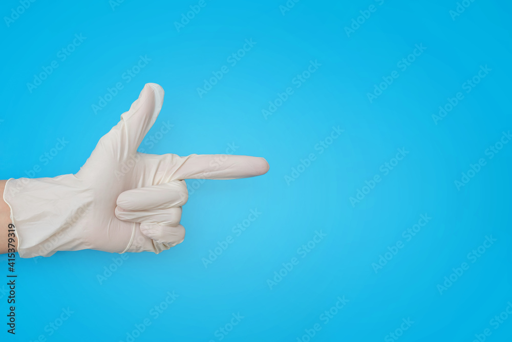 a hand in white medical gloves points to the open space. pointing finger of a medical worker on a blue background copy space