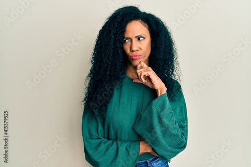 Middle age african american woman wearing casual clothes thinking concentrated about doubt with finger on chin and looking up wondering