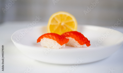 side view, white plate with sushi and lemon on a white background, red fish on rice