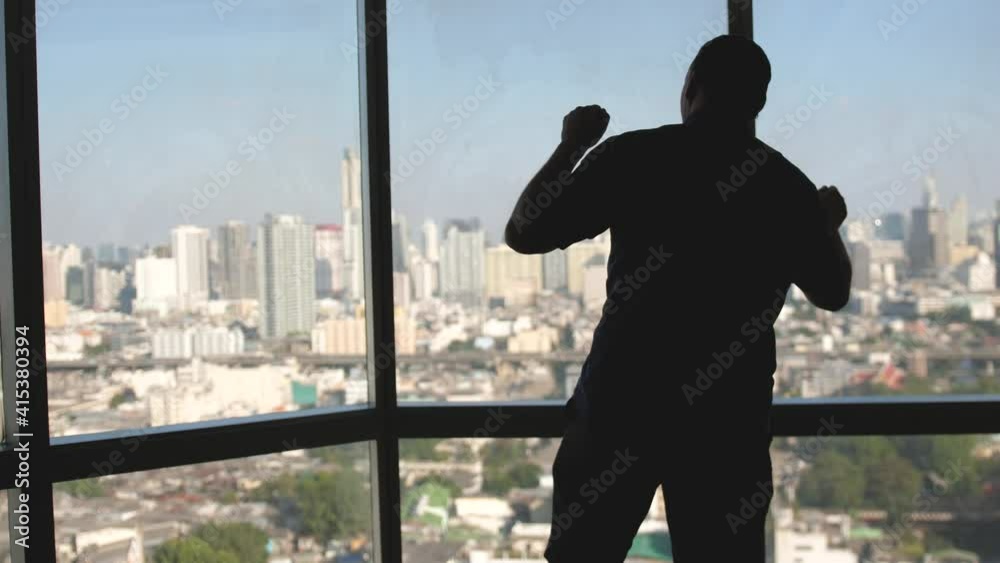 Back view cheerful businessman standing near large window and dancing. Man having fun and relaxing looking through panoramic window. slow motion Back view cheerful businessman standing near large window and dancing. Man having fun and relaxing looking through panoramic window. slow motion
