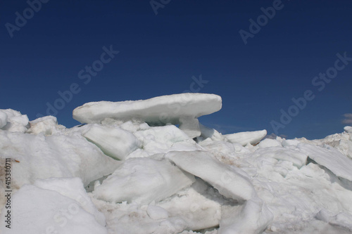 Ice hummocks on the shoals of the frozen bay against a blue sky on a sunny day. Natural cold background