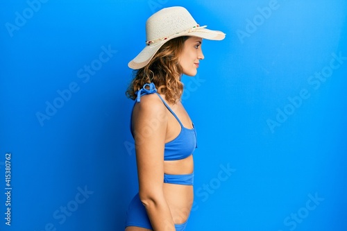 Young caucasian woman wearing bikini and summer hat looking to side, relax profile pose with natural face with confident smile. © Krakenimages.com