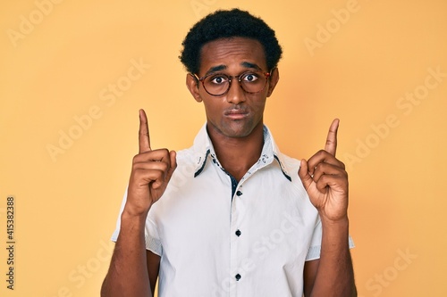 Foto African handsome man pointing up with fingers depressed and worry for distress, crying angry and afraid