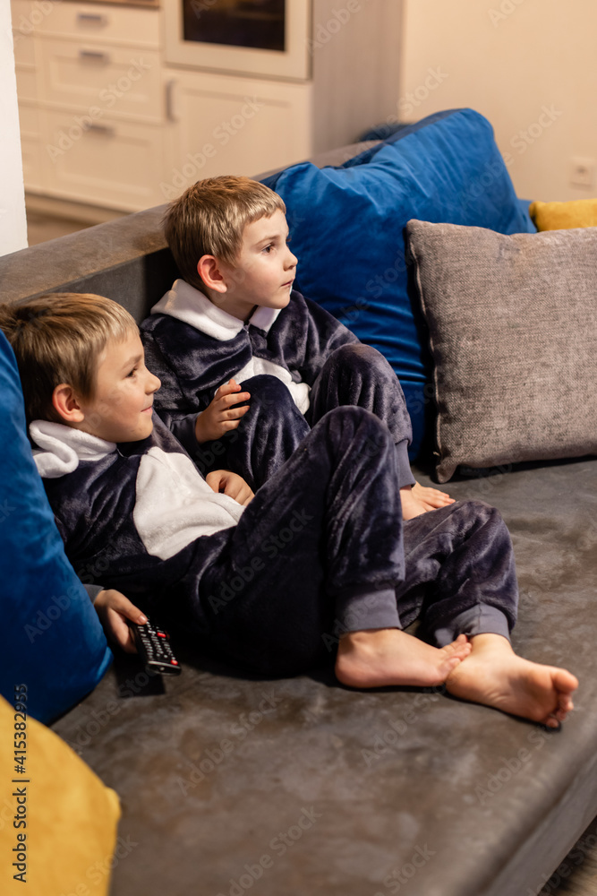 Obraz premium the little brothers in kigurumi watching tv at home
