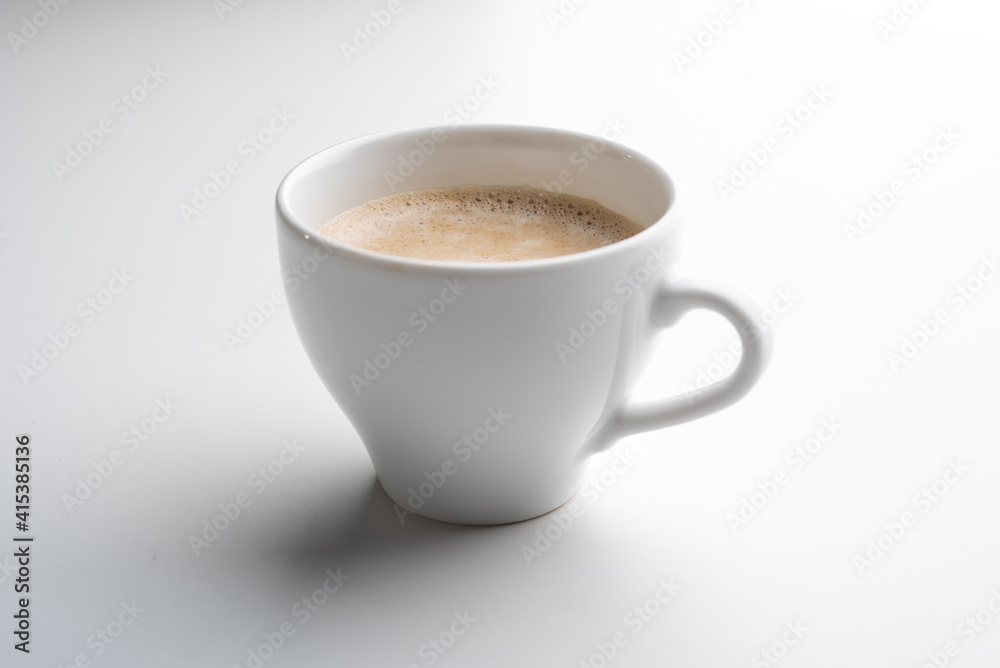 White cup of coffee in soft light isolated on a white background. Cappuccino coffee. White cup of coffee in soft light isolated on a white background. Cappuccino coffee.
