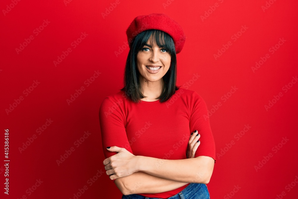 Young hispanic woman wearing french look with beret happy face smiling with crossed arms looking at the camera. positive person.