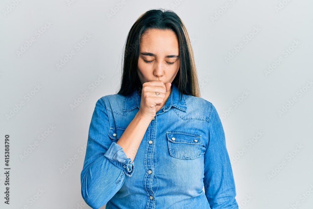 Young hispanic woman wearing casual denim jacket feeling unwell and coughing as symptom for cold or bronchitis. health care concept. Young hispanic woman wearing casual denim jacket feeling unwell and coughing as symptom for cold or bronchitis. health care concept.