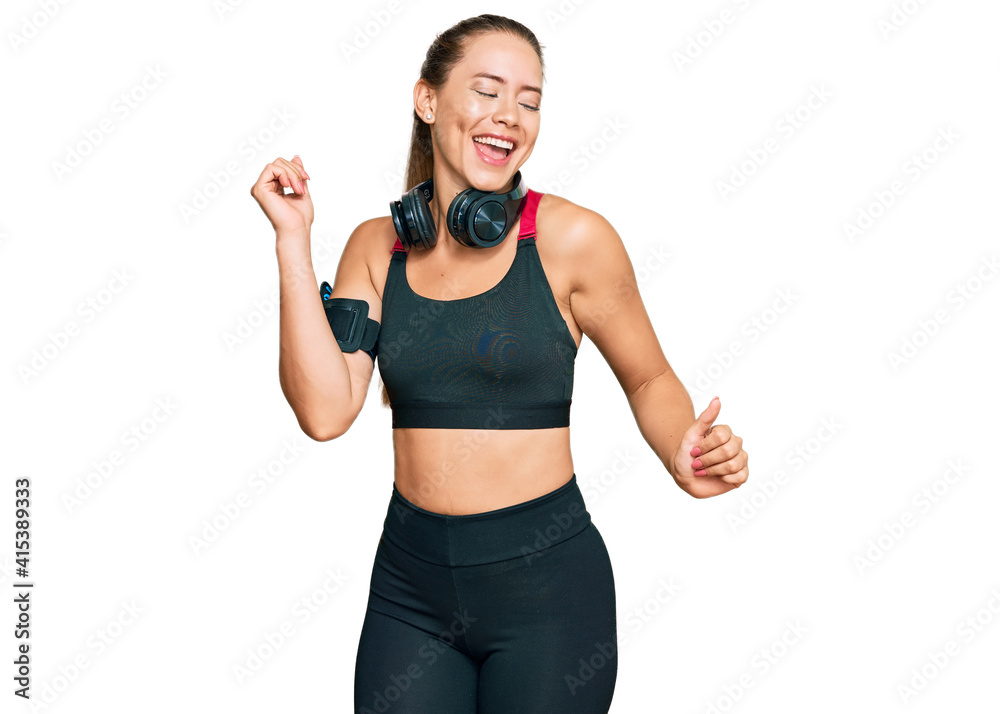 Beautiful blonde woman wearing gym clothes and using headphones dancing happy and cheerful, smiling moving casual and confident listening to music Beautiful blonde woman wearing gym clothes and using headphones dancing happy and cheerful, smiling moving casual and confident listening to music