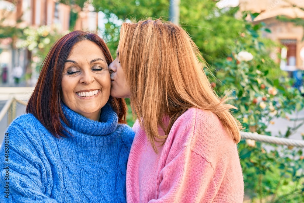 Hispanic mother and daughter smiling happy. Standing with smile on face hugging and kissing at the park. Hispanic mother and daughter smiling happy. Standing with smile on face hugging and kissing at the park.