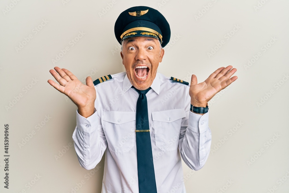 Handsome middle age mature man wearing airplane pilot uniform celebrating crazy and amazed for success with arms raised and open eyes screaming excited. winner concept