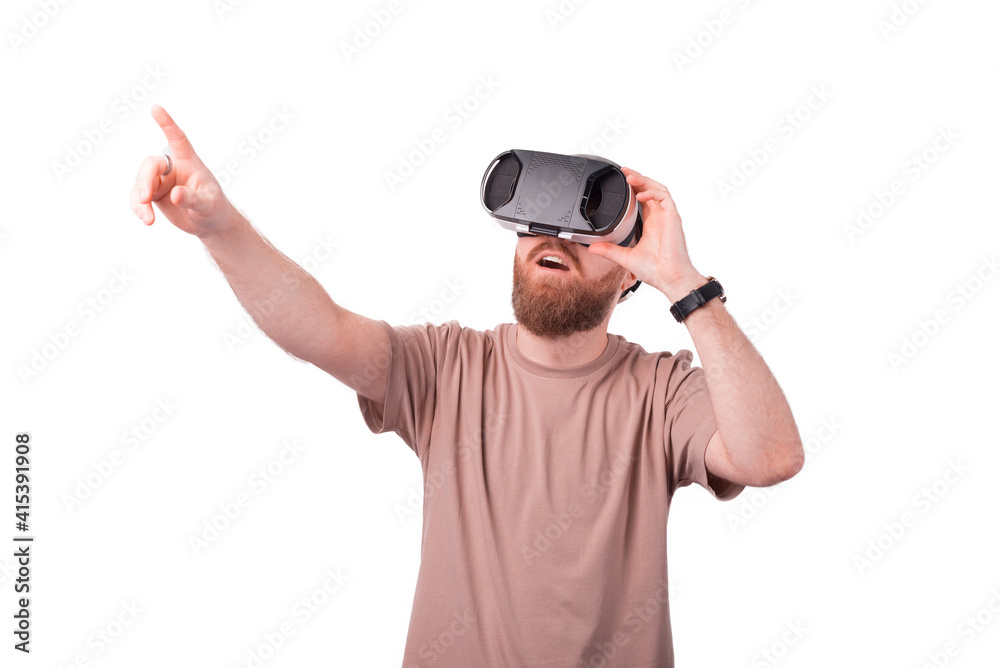 Naklejka premium Young bearded man pointing away and wearing VR glasses, Virtual reality experience
