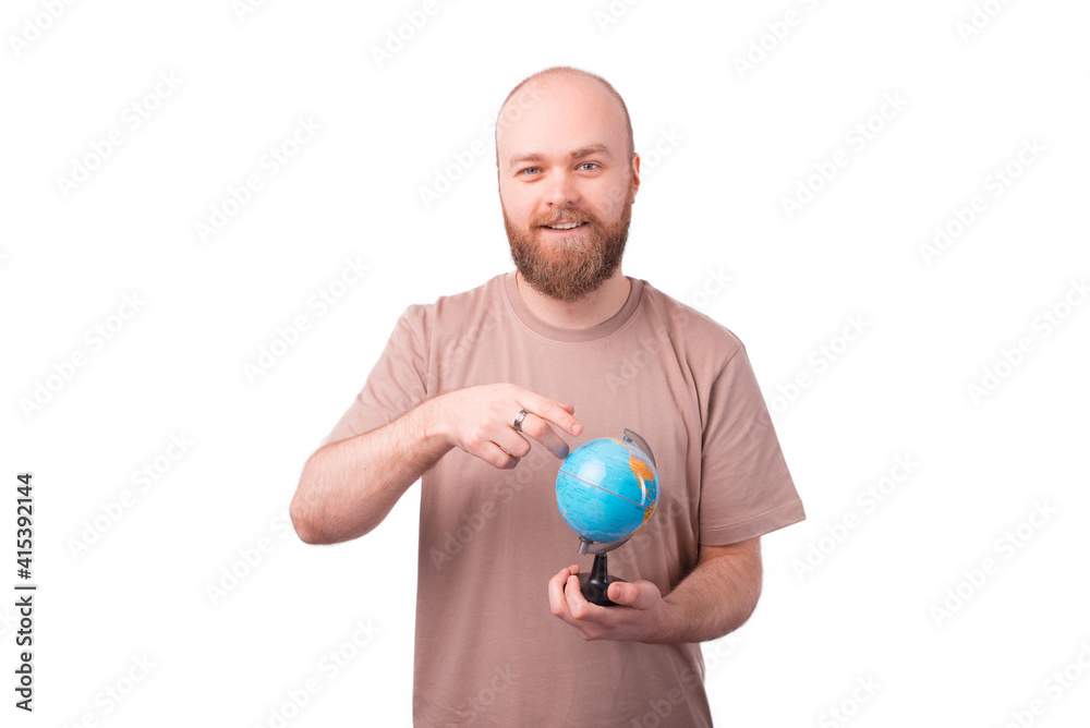 Portrait of young bearded man pointing at globe, travel concept Portrait of young bearded man pointing at globe, travel concept