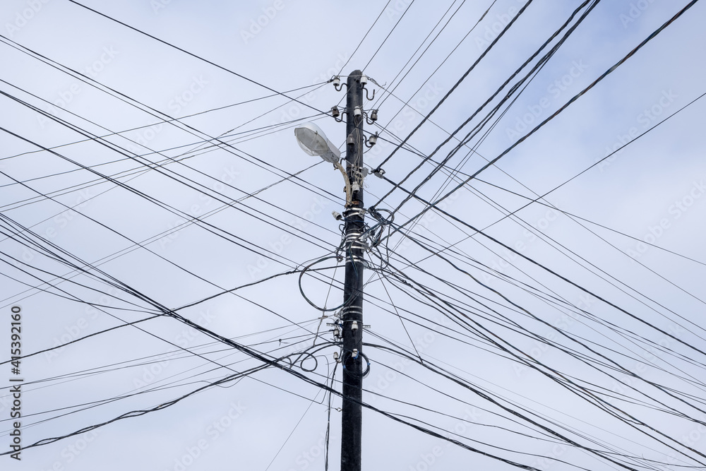 Land Line Messy black electric wires cables on Electric poles. against the cloudy sky Land Line Messy black electric wires cables on Electric poles. against the cloudy sky