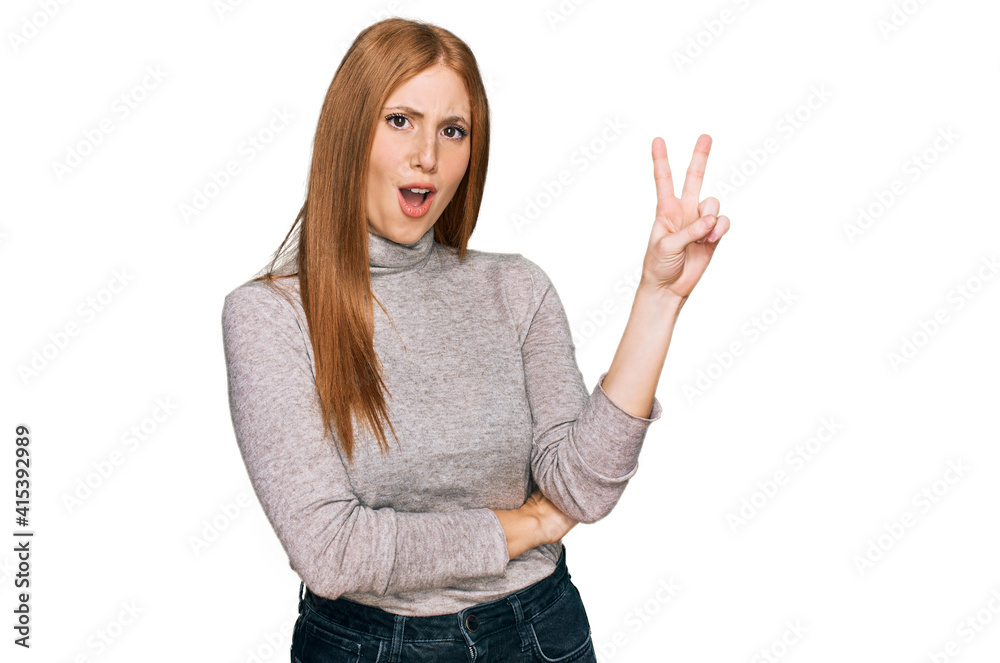 Young irish woman wearing casual clothes smiling with happy face winking at the camera doing victory sign. number two. Young irish woman wearing casual clothes smiling with happy face winking at the camera doing victory sign. number two.