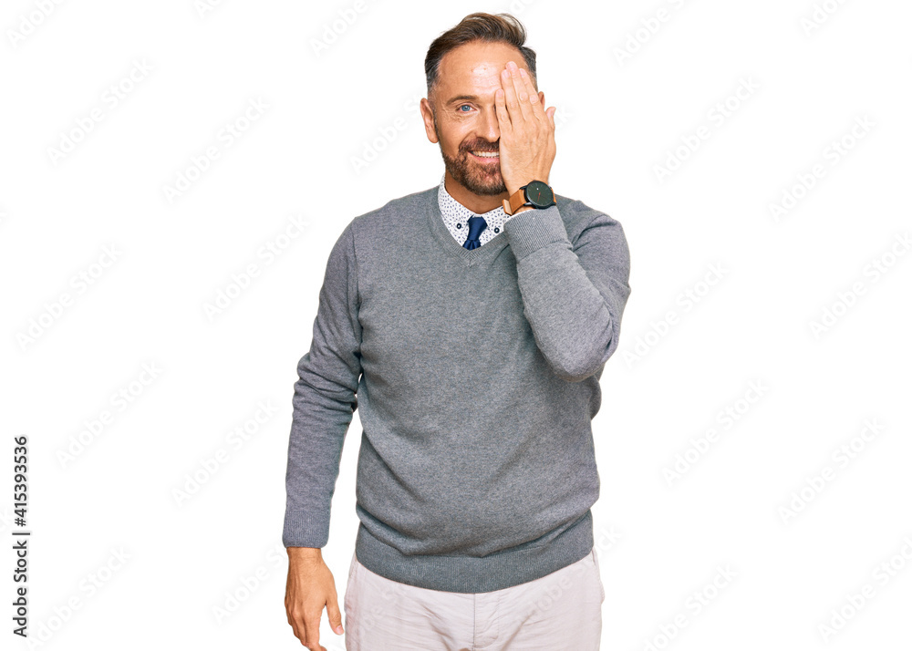 Handsome middle age man wearing business clothes covering one eye with hand, confident smile on face and surprise emotion. Handsome middle age man wearing business clothes covering one eye with hand, confident smile on face and surprise emotion.