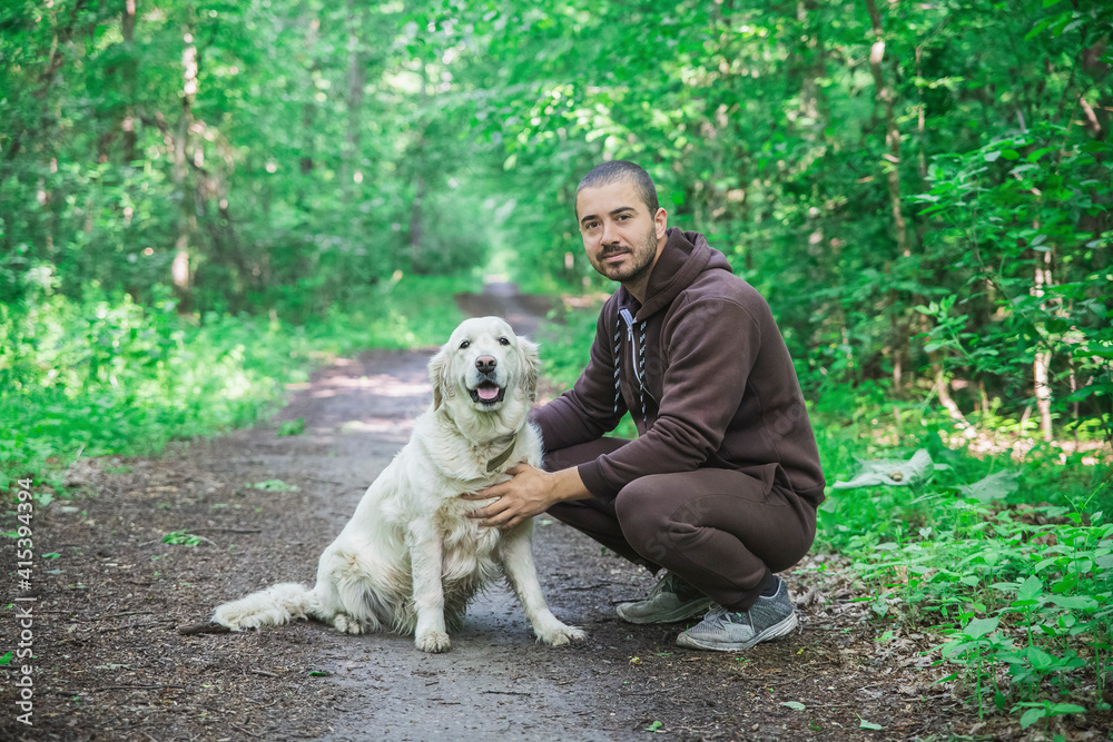 man in a tracksuit walks a dog in the forest