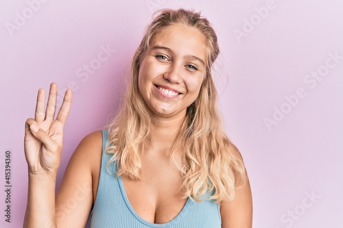 Young blonde girl wearing casual clothes showing and pointing up with fingers number three while smiling confident and happy.