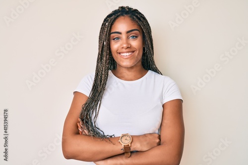 Young african american woman with braids wearing casual white tshirt happy face smiling with crossed arms looking at the camera. positive person.