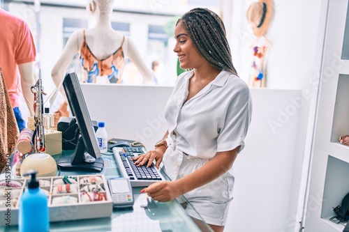 Young african american woman smiling happy working at the till at retail shop