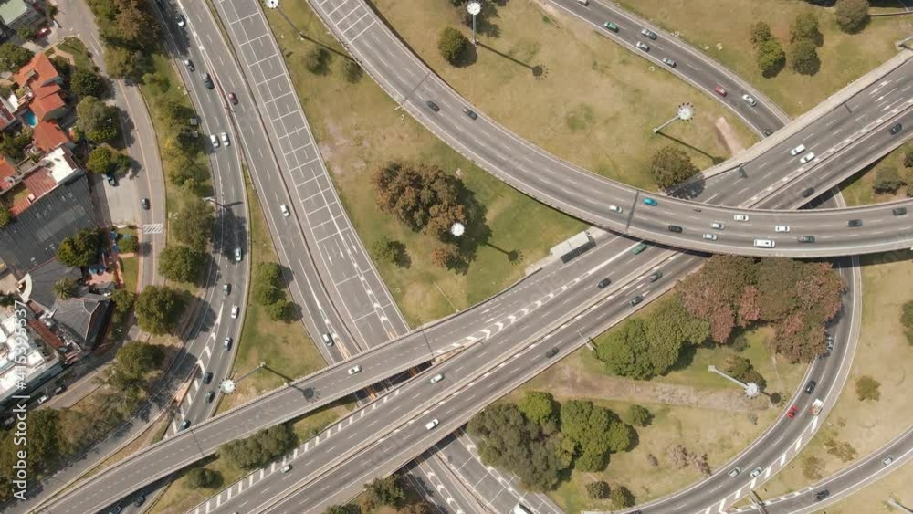 Aerial top down shot rising over traffic driving on a highway interchange. Wide view Aerial top down shot rising over traffic driving on a highway interchange. Wide view