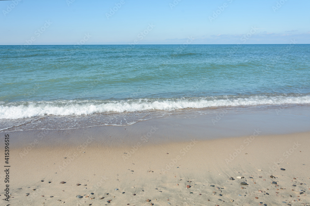 Sandy seashore with small stones. Surf and wave with white foam close-up. Travel concept, sea vacation