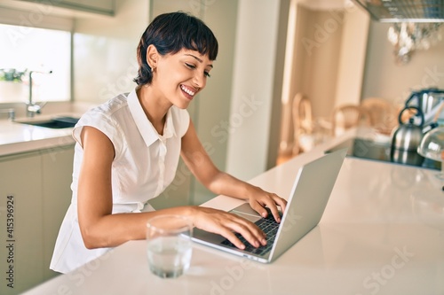 Beautiful brunette woman with short hair at home using computer laptop