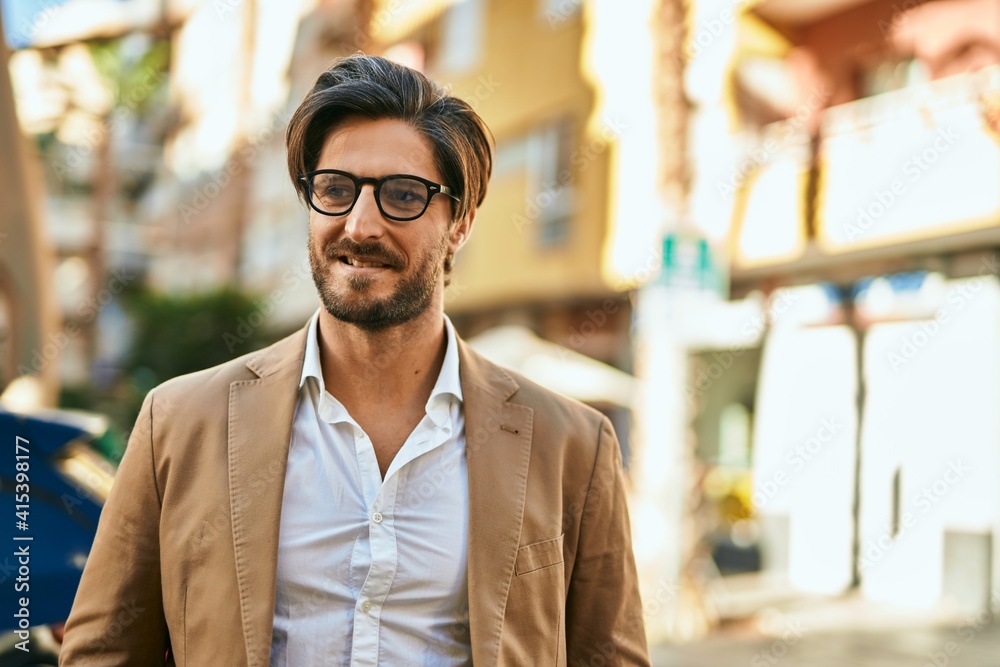 Obraz premium Young hispanic businessman smiling happy standing at the city.